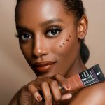 Elegant portrait of a woman showcasing skincare product with flawless makeup and glowing skin.